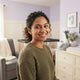 A happy parent smiling in a bright, modern nursery with soft lavender and warm cream accents.
