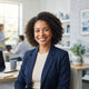 A diverse woman smiling in a professional office setting with soft blue ambient decor.